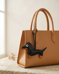The Dachshund Charm in black on a camel leather tote