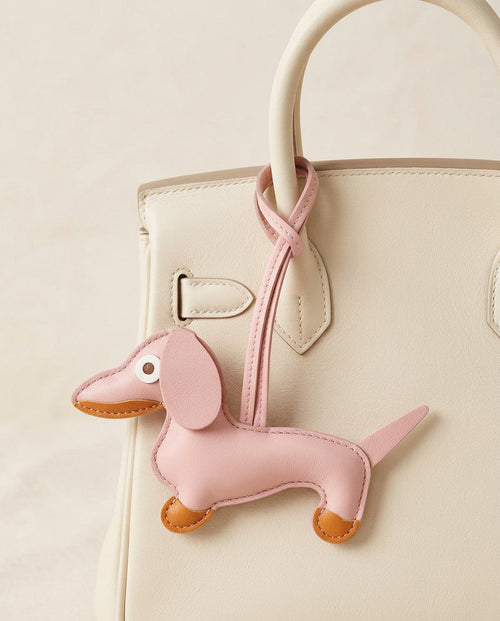 The Dachshund Charm in pale pink on a cream handbag